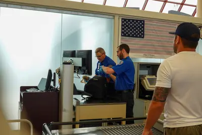 TSA Security employees checking a backpack