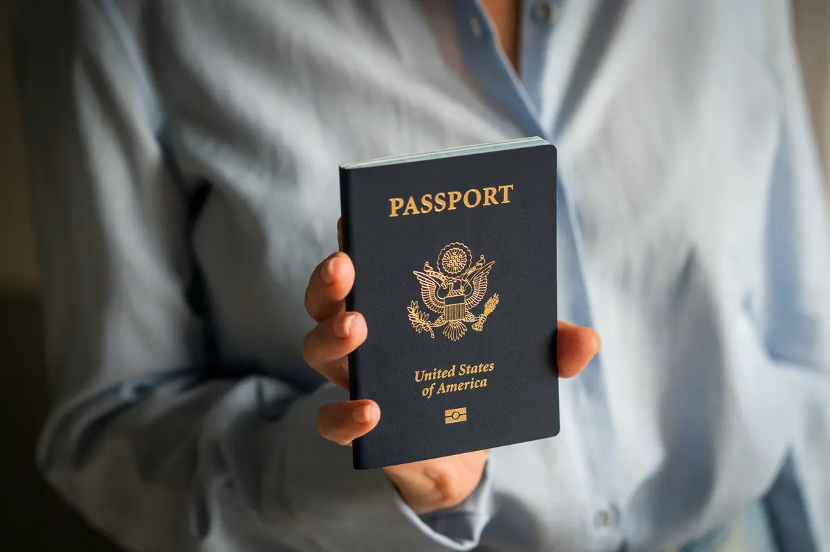 woman in blue shirt showing American citizen passport