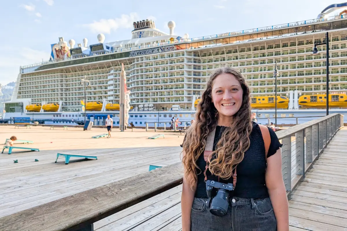 Jenna smiling in front of Anthem of the Seas cruise ship docked in Juneau